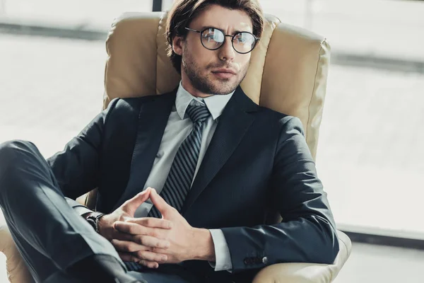 ハンサムな思いやりのある実業家の肘掛け椅子に座っていると近代的なオフィスを離れて見て — ストック写真