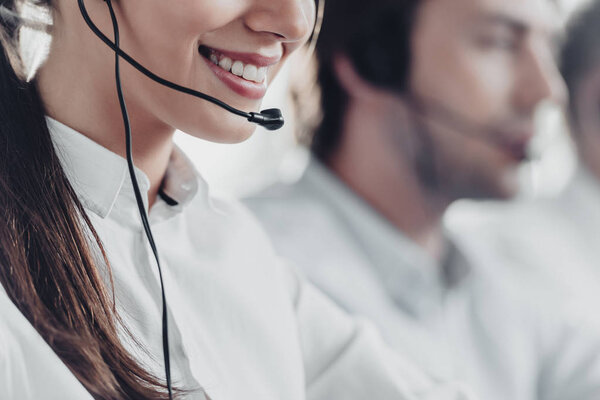 cropped shot of smiling young call center manageress working with colleagues
