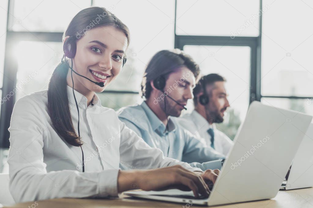 happy call center managers working with laptops and microphones at modern office