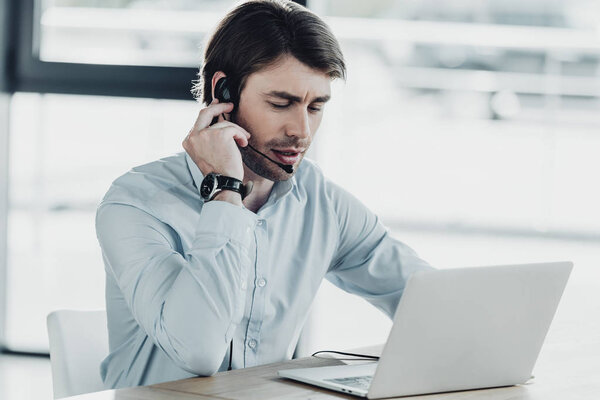 confident call center worker with laptop sitting at workplace