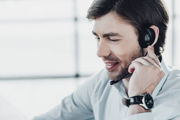 smiling support hotline worker in headphones with microphone at work