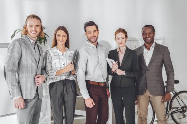 ayakta ve kameraya bakarak çok kültürlü iş adamları gülümseyen