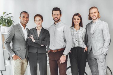 ayakta ve kameraya bakarak çok kültürlü iş adamları gülümseyen