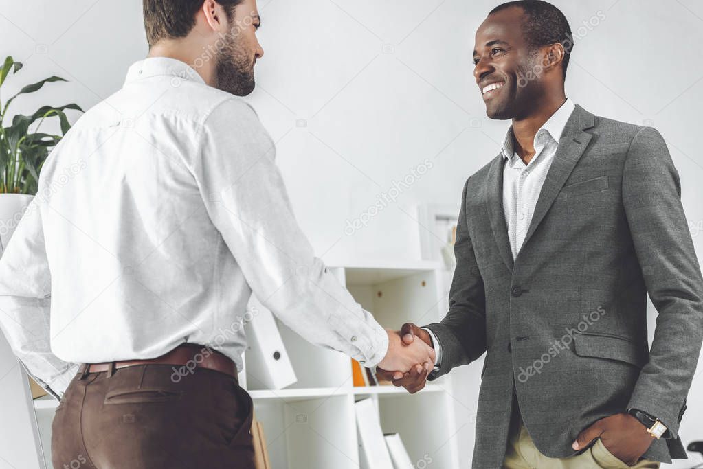 smiling african american and caucasian businessmen shaking hands