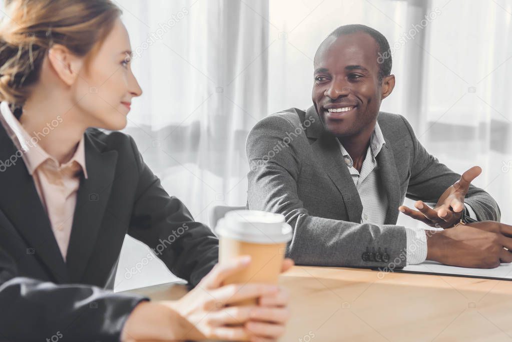 african man smiling to woman with coffe in hands  at office space