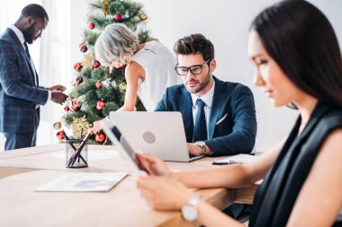 Beyaz işadamı çalışma ve çok kültürlü meslektaşları ofiste Noel ağacı süsleme
