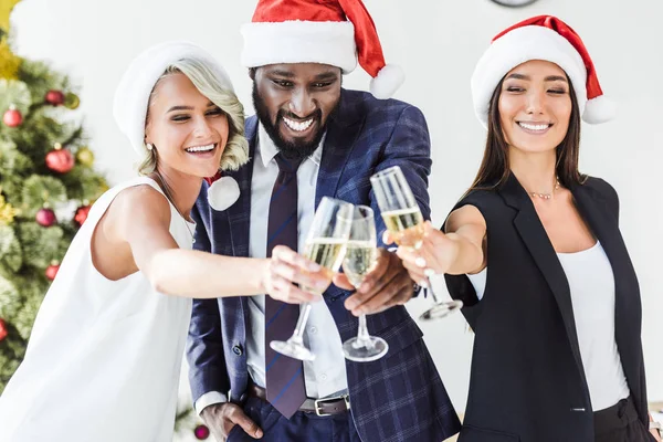 微笑的多文化商人在圣诞老人帽子无比与香槟在办公室里 — 图库照片