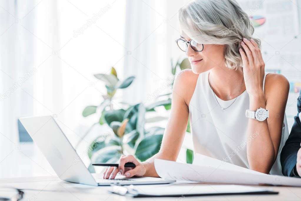 side view of beautiful caucasian businesswoman using laptop in office