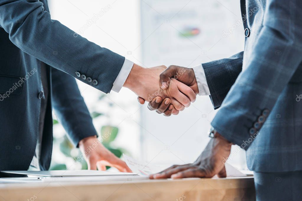 cropped image of multiethnic businessmen shaking hands in office