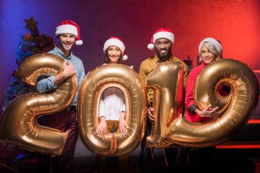 Noel Baba şapkaları 2019 Balonlar yeni yıl şirket partisinde holding içinde çok ırklı iş adamları gülümseyen