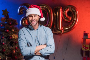 santa şapka ayakta yeni yıl şirket partisinde çapraz kollu yakışıklı işadamı