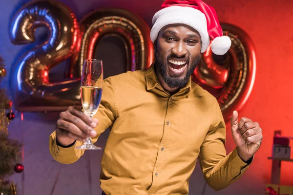 新年企業パーティーでシャンパン グラスを持ってサンタ帽子で幸せなアフリカ系アメリカ人実業家 — ストック写真