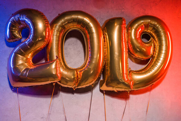 golden 2019 sign helium balloons with blue and red light on grey