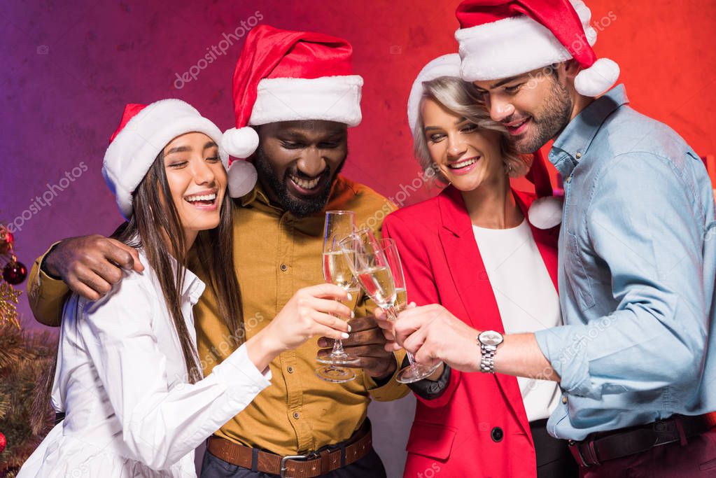 young multicultural businesspeople clinking with glasses of champagne at new year corporate party 