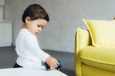adorable kid playing with toy car at home clipart