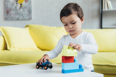 küçük çocuk Oluşturucu blokları ve oyuncak araba masada evde oynamaya