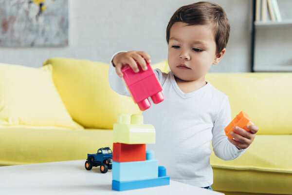 милый малыш играет с красочными блоками конструктора на столе
