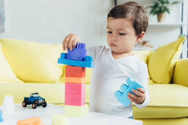 adorable little boy playing with constructor blocks and toys at home