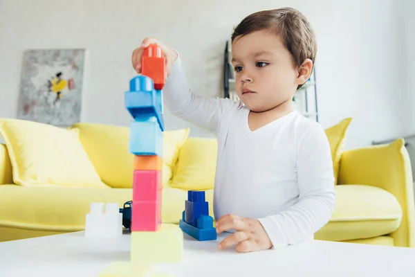 かわいい子供は自宅のテーブルの上のカラフルなコンス トラクター ブロックで遊んで — ストック写真