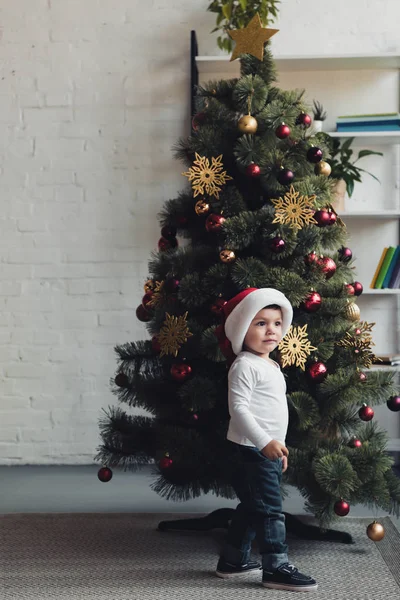 Cute Kid Santa Hat Standing Christmas Tree Home — Free Stock Photo