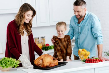 beautiful little child preparing thanksgiving dinner with parents clipart