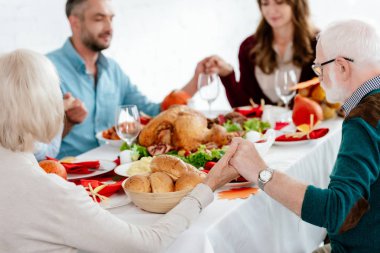 selective focus of family praying at served table with turkey before holiday dinner on thanksgiving  clipart