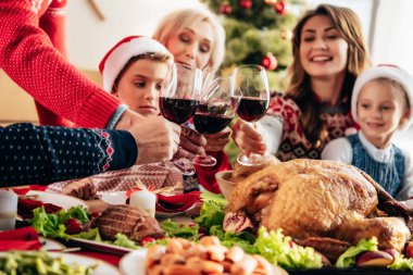 ailesinin evde Noel akşam yemeği sırasında tarafından şarap bardakları tokuşturup resim kırpılmış 