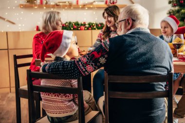komuta sizde kucaklayan torunu evde ailesi ile tatil yemek sırasında Noel şapkalı dikiz