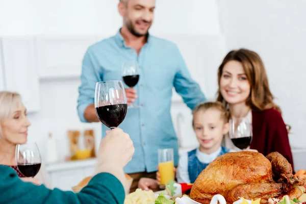 selective focus of family with wine glasses celebrating thanksgiving at served table