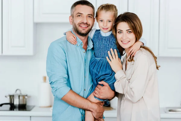 Retrato Familia Feliz Sosteniendo Abrazando Pequeña Hija Mirando Cámara Cocina — Foto de Stock
