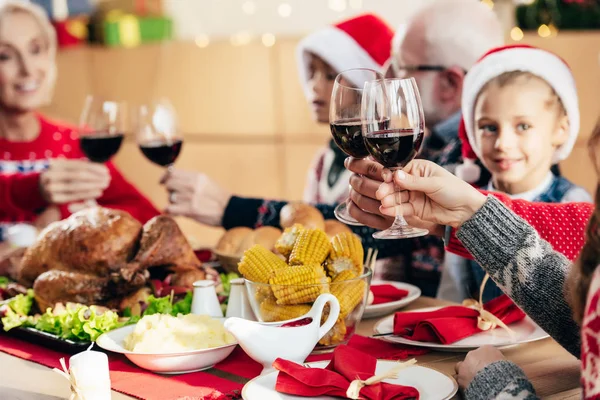 partial view of family clinking by wine glasses during christmas dinner at home