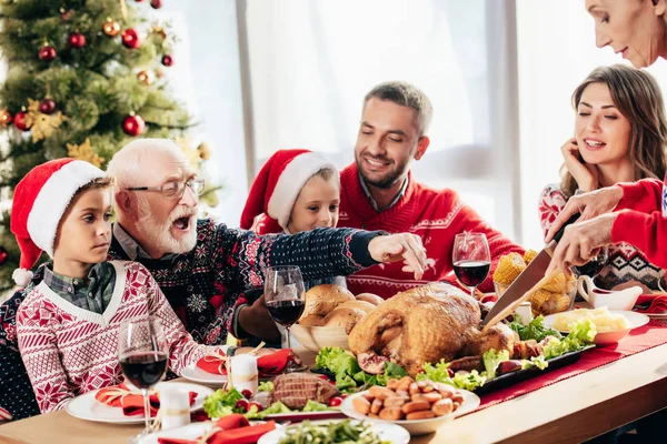 Mulher Sênior Cortando Peru Para Jantar Natal Com Família Feliz — Fotografia de Stock