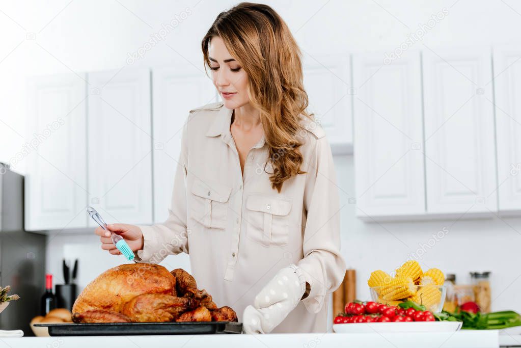 beautiful happy woman cooking thanksgiving turkey at kitchen