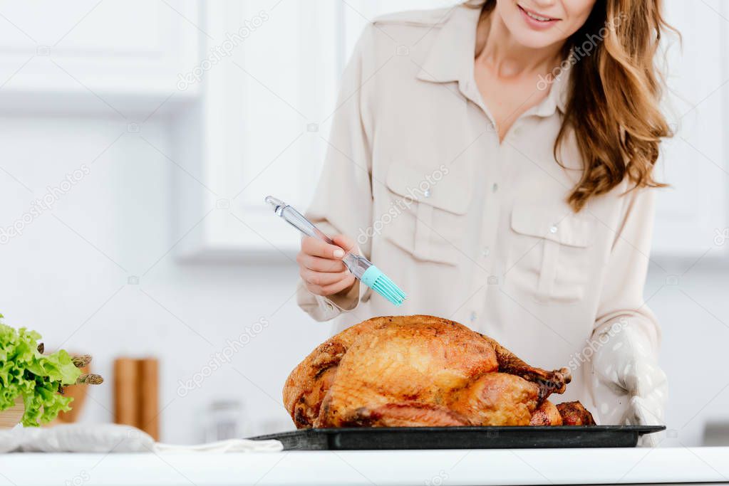 cropped shot of woman cooking thanksgiving turkey at kitchen