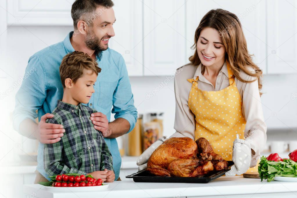 little kid with parents preparing thanksgiving turkey together at kitchen