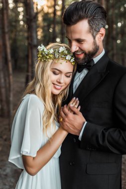 beyaz elbise ve yakışıklı damat sarılma ve ormanda elele elbiseli güzel mutlu gelin 