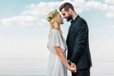 Evlilik çift elele ve plajda burunlu dokunmadan takım elbise ve beyaz elbise