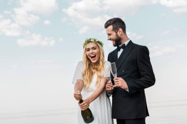 Sahilde şampanya şişe açılış beyaz elbiseli mutlu gelin