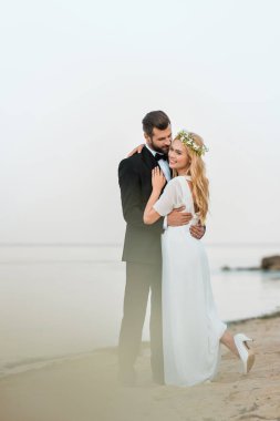 Okyanusu yakınlarındaki kum plajındaki sarılma düğün çifti