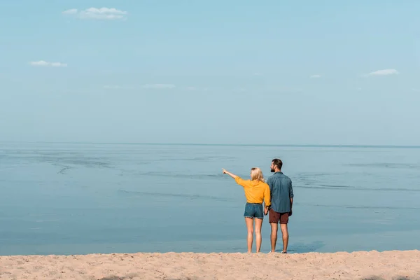 Kézenfogva Strandon Barátnője Valami Mutat Pár Hátulnézete — Stock Fotó