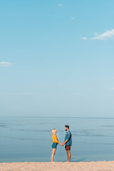 couple holding hands and looking at each other on beach