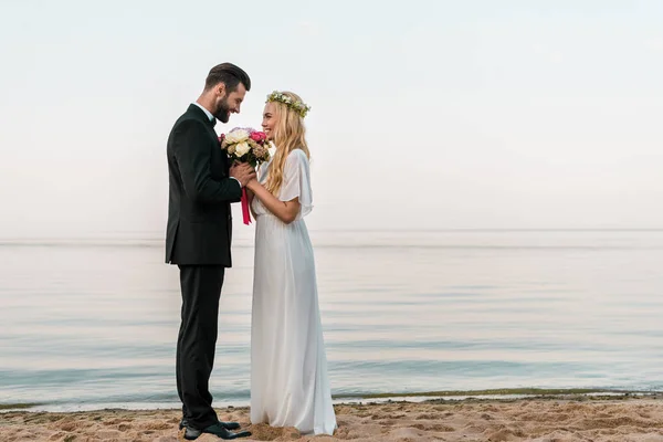 Vista Lateral Casal Casamento Afetuoso Com Buquê Praia Noiva Farejando — Fotografia de Stock