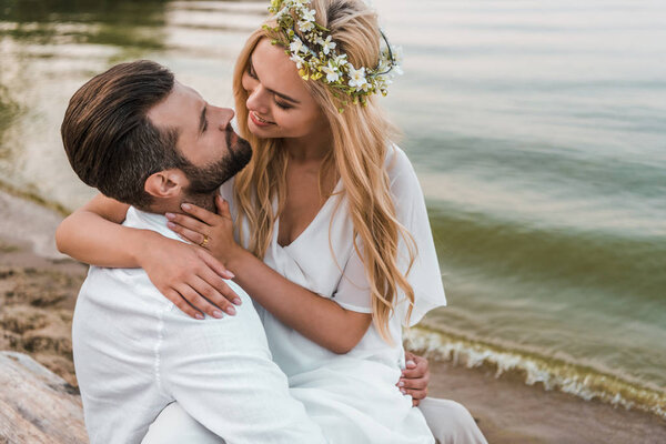 smiling elegant bride and groom going to kiss on beach