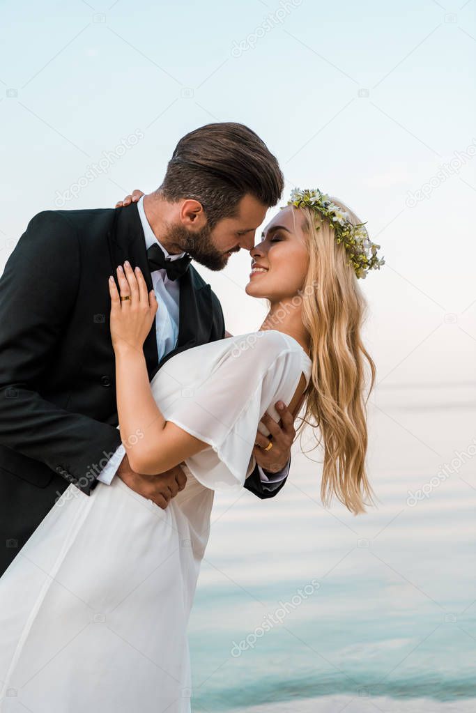 affectionate romantic wedding couple going to kiss on beach