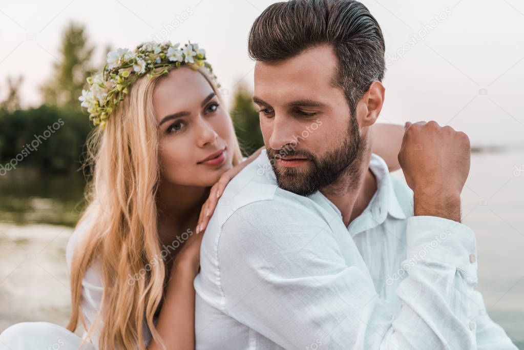portrait of beautiful bride in wreath and handsome groom on beach 