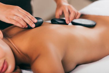 cropped view of young woman having stone therapy at massage salon  clipart