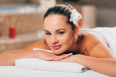 Spa salon de rahatlatıcı ve kameraya bakarak güzel genç kadın
