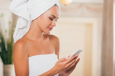 spa salon de akıllı telefon kullanan genç gülümseyen kadın