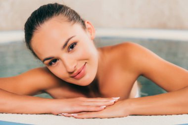 spa salonda yüzme havuzunda rahatlatıcı ve kameraya bakarak kadın