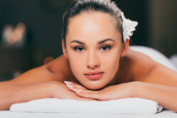 young woman white flower in her hair looking at camera